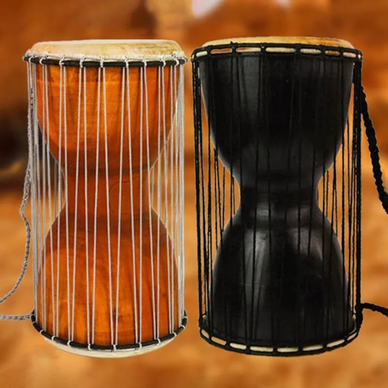 Dois tambores djembe artesanais, um marrom e um preto, com cordas e cabo de transporte, sobre fundo amarronzado.