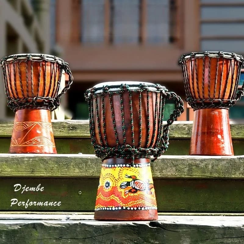 Três djembes africanos pequenos em uma escada de madeira com decorações africanas