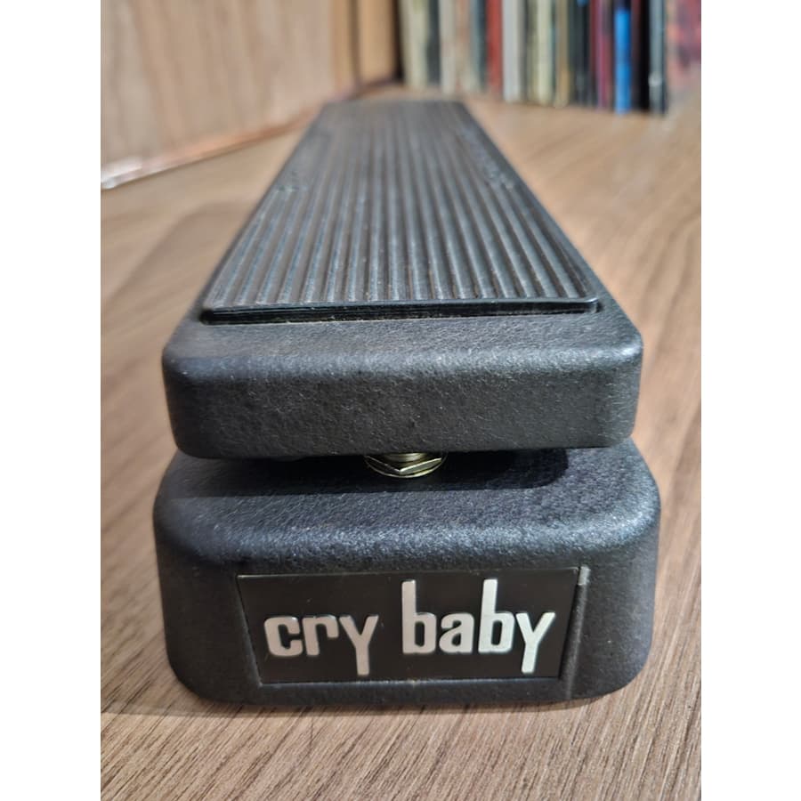 Pedal de efeito de guitarra Cry Baby GCB95 usado, Jim Dunlop, em pé sobre uma mesa de madeira, ângulo frontal.