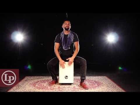 Músico tocando cajon LP Aspire LPA1331 natural em palco com fundo preto e iluminação de palco.