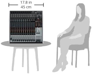 Mesa de som Behringer X2442USB sobre mesa com 45 cm largura comparada ao tamanho de pessoa sentada ao lado.