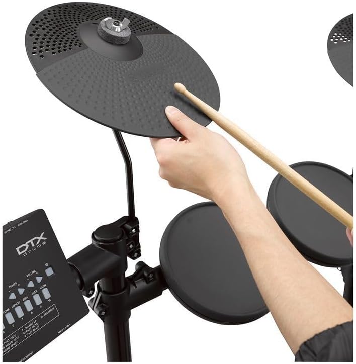 Prato eletrônico preto da bateria Yamaha DTX452K sendo tocado com baqueta de madeira
