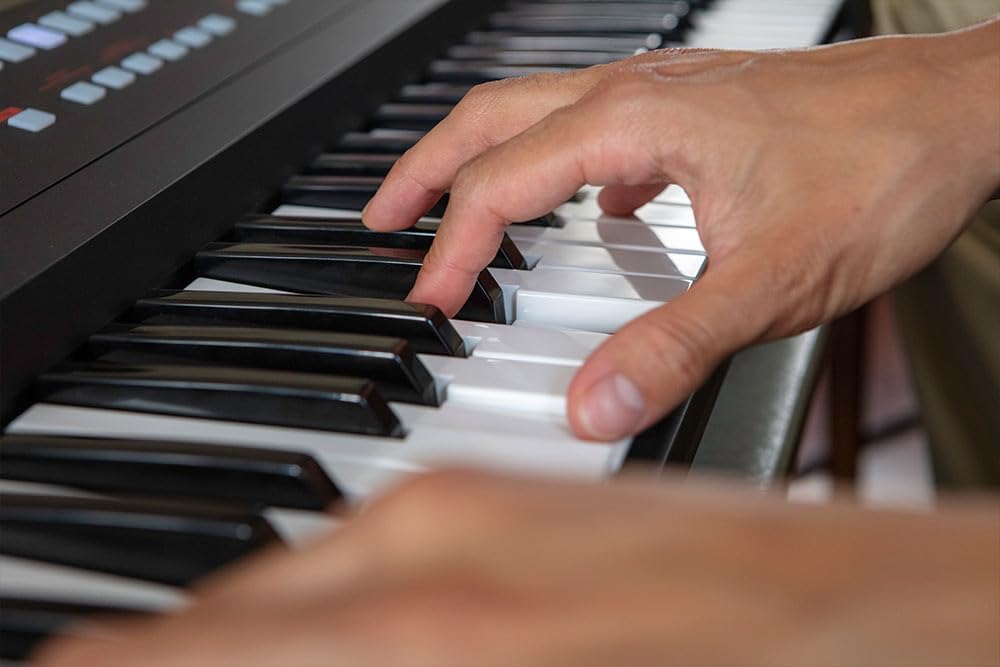 Mãos tocando teclas do teclado arranjador Roland E-X50 em close