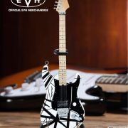 Guitarra mini réplica AXE HEAVEN EVH003 feita à mão branca com listras pretas e braço de madeira clara em suporte.