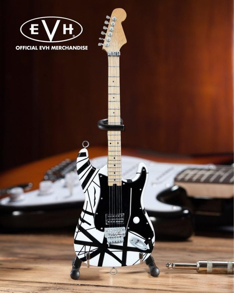 Guitarra mini réplica AXE HEAVEN EVH003 feita à mão branca com listras pretas e braço de madeira clara em suporte.