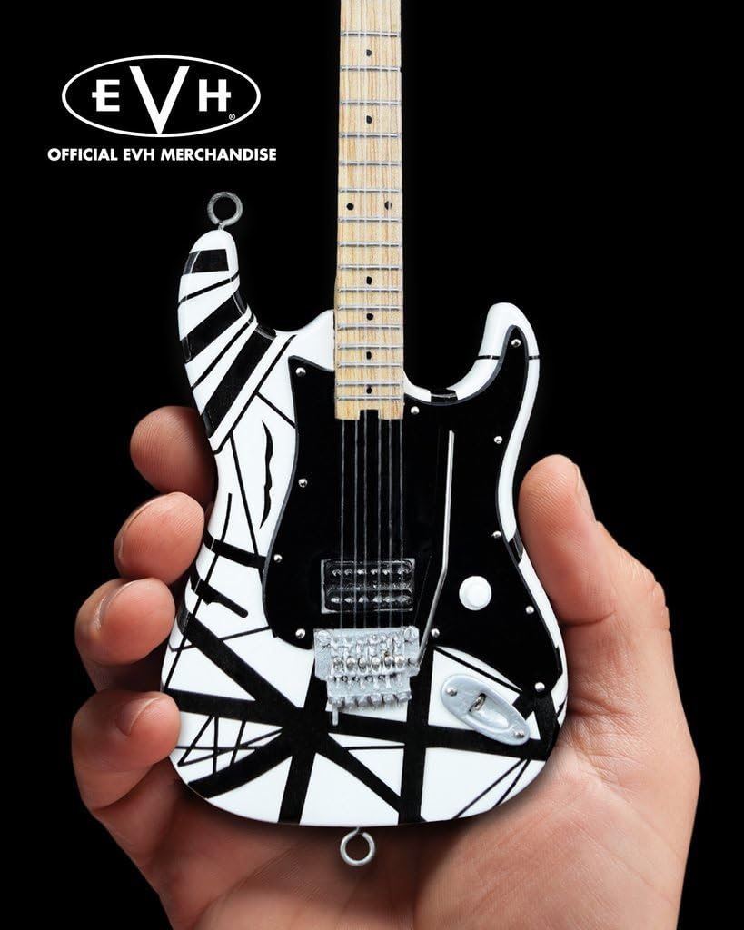 Mini guitarra AXE HEAVEN EVH003 com corpo branco e listras pretas sobre fundo preto segurada por mão.