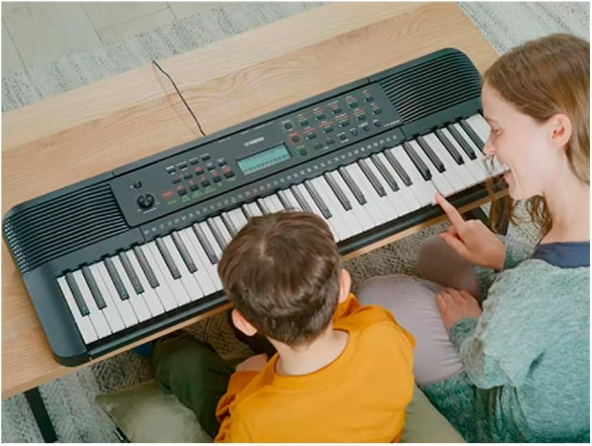 Crianças usando teclado portátil Yamaha PSR-E283 preto com 61 teclas em ambiente doméstico