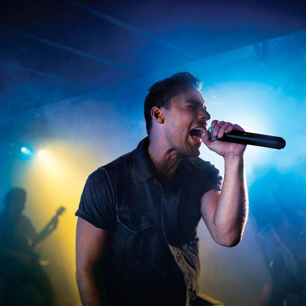 Vocalista cantando com microfone sem fio Shure BLX24/SM58 em show ao vivo com luzes azuis e amarelas