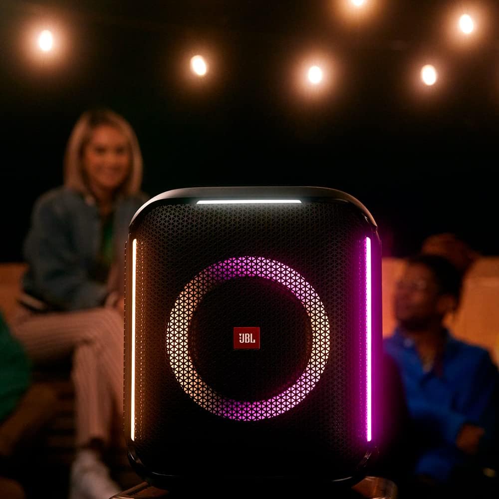 JBL PartyBox Encore caixa de som Bluetooth preta com iluminação LED em uso noturno com pessoas ao fundo