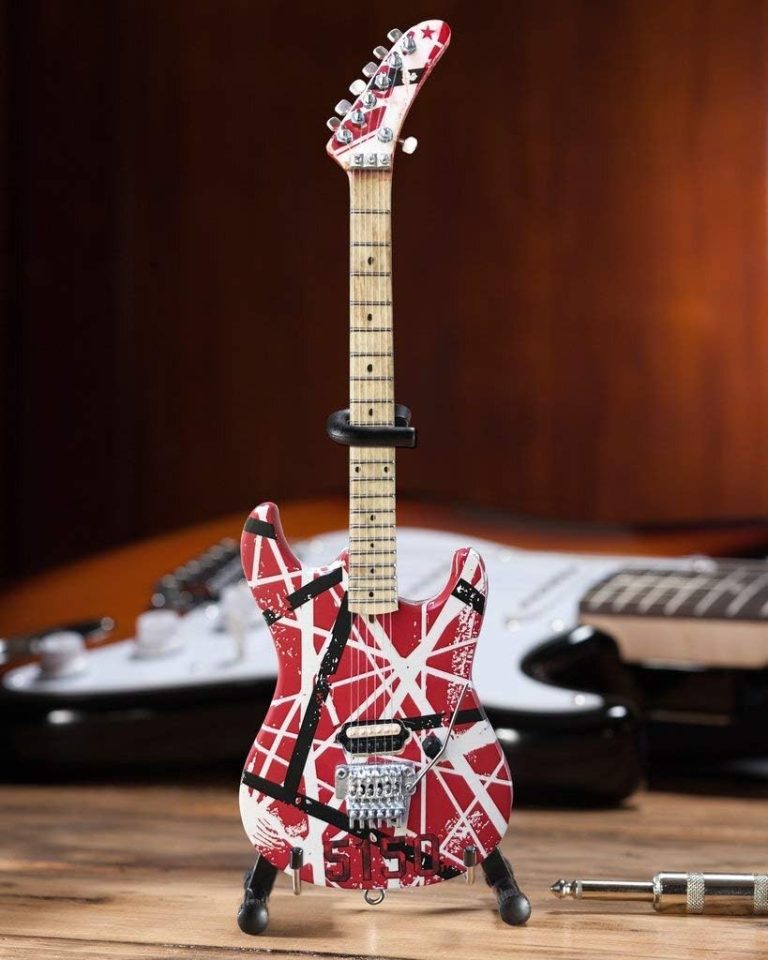 Miniatura decorativa de guitarra elétrica Axe Heaven EVH004 vermelha com listras brancas e pretas em suporte preto.