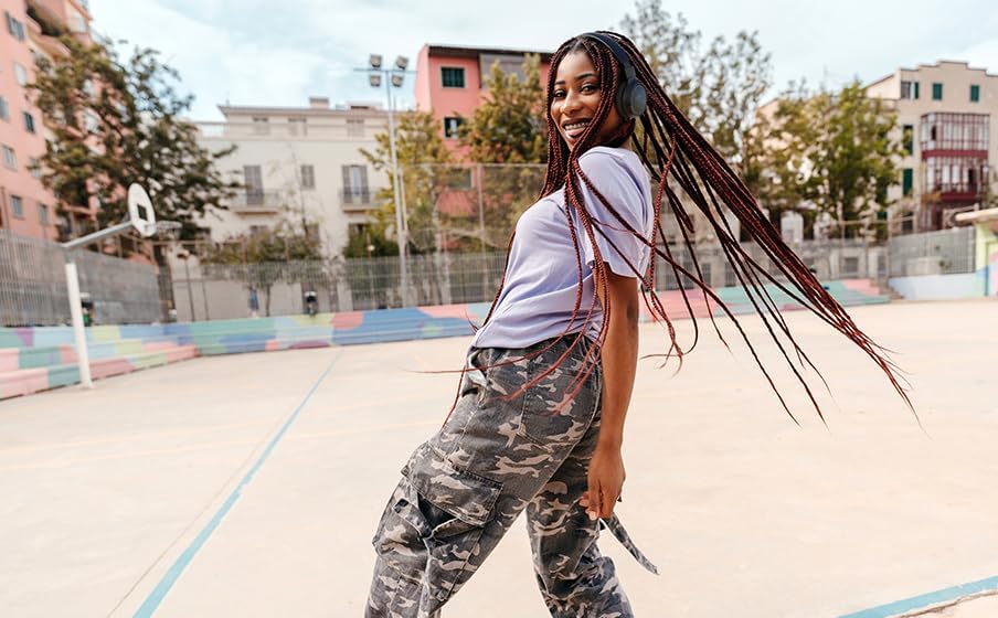 Mulher jovem usando fones de ouvido Bluetooth JBL Tune 520BT pretos em quadra de basquete