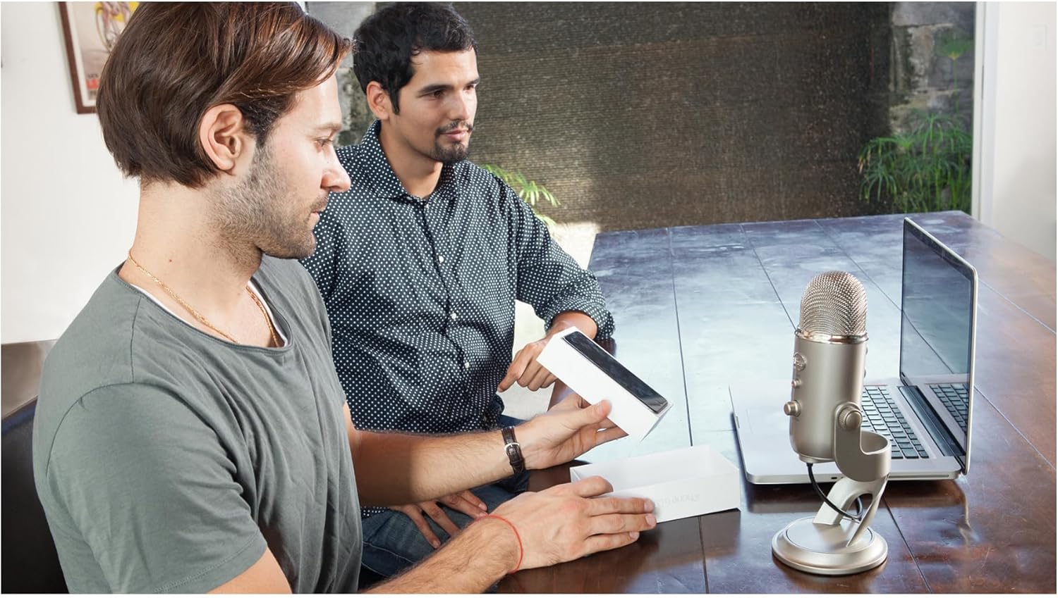 Homens interagindo com microfone Blue Yeti prateado conectado a laptop