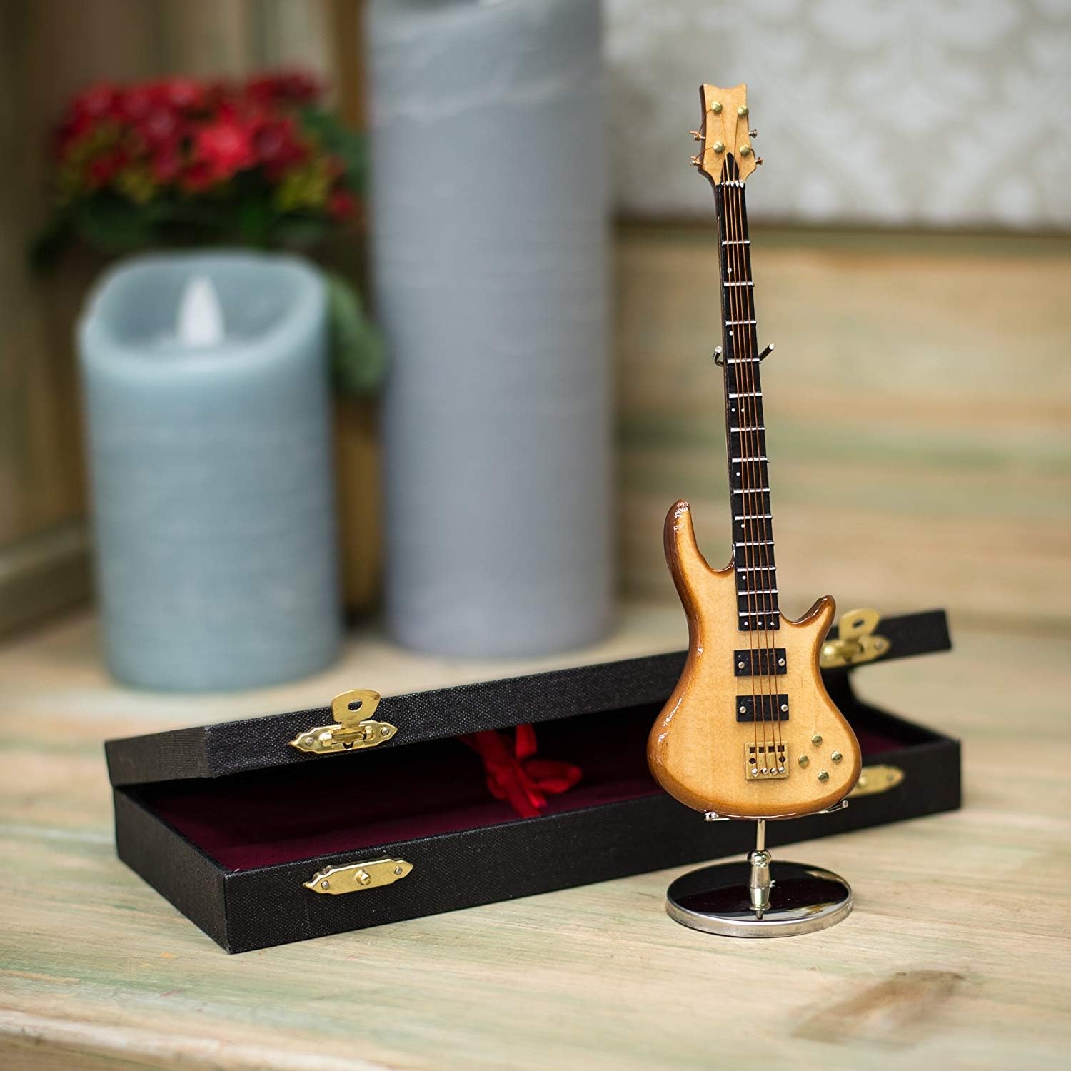 Miniatura de guitarra elétrica de baixo dourada com suporte metálico e estojo preto aberto em fundo interno decorativo Broadway Gifts