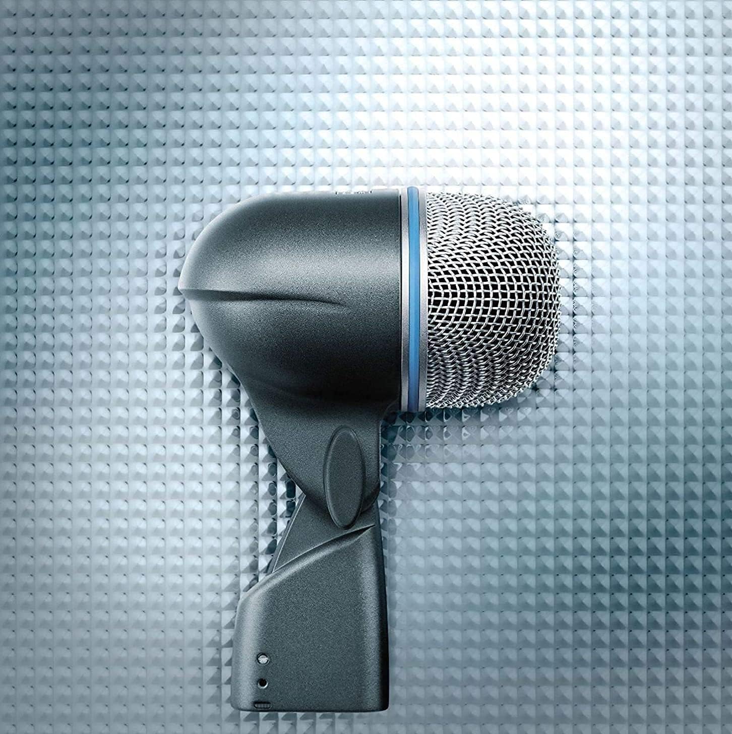 Microfone Shure BETA 52A dinâmico supercardióide para bateria sobre superfície texturizada cinza.