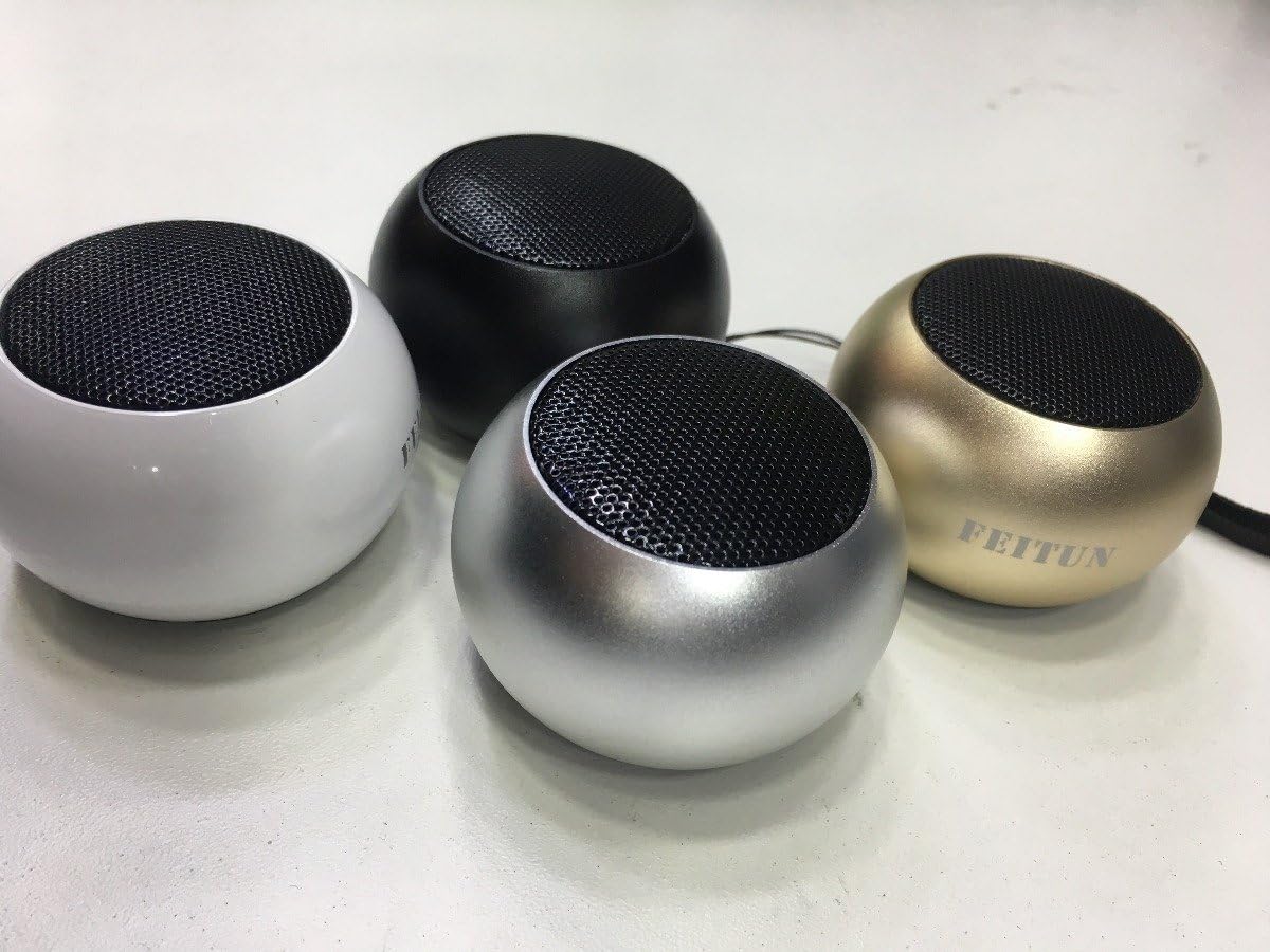 Caixinhas de som Bluetooth portáteis Feitun Fn-0006 em cores branco, preto, prata e dourado, formato compacto e arredondado.