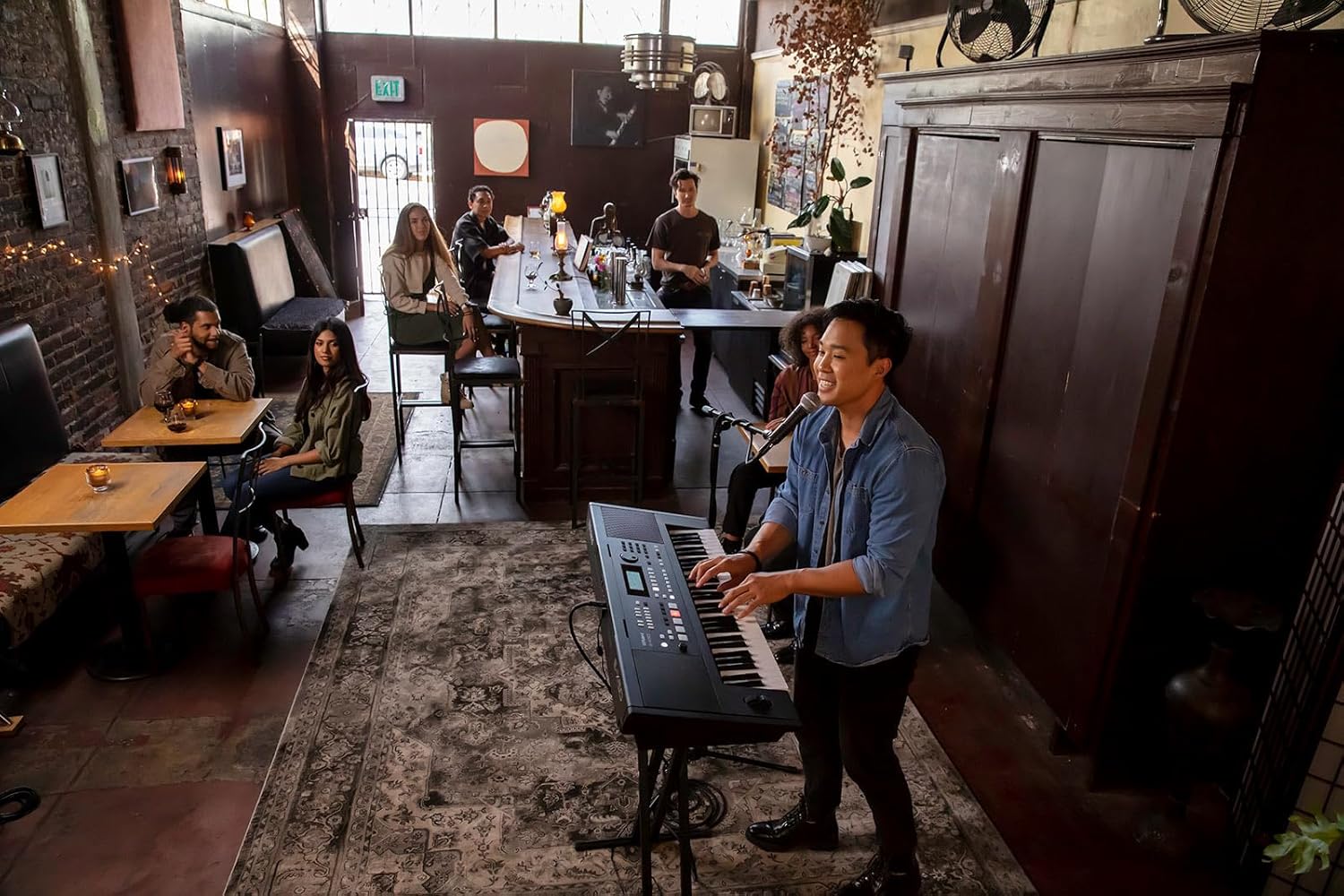 Jovem tocando teclado Roland E-X50 em café com público atento