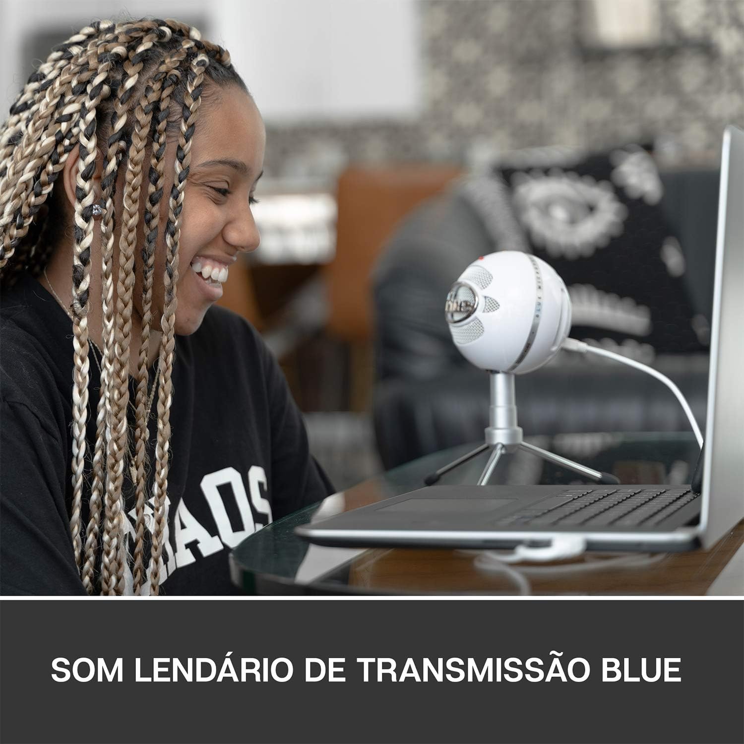 Pessoa usando microfone Blue Snowball iCE branco com suporte tripé conectado em notebook, som lendário de transmissão