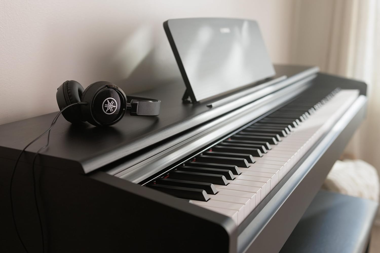 Teclado piano digital Yamaha com fones de ouvido pretos em ambiente claro