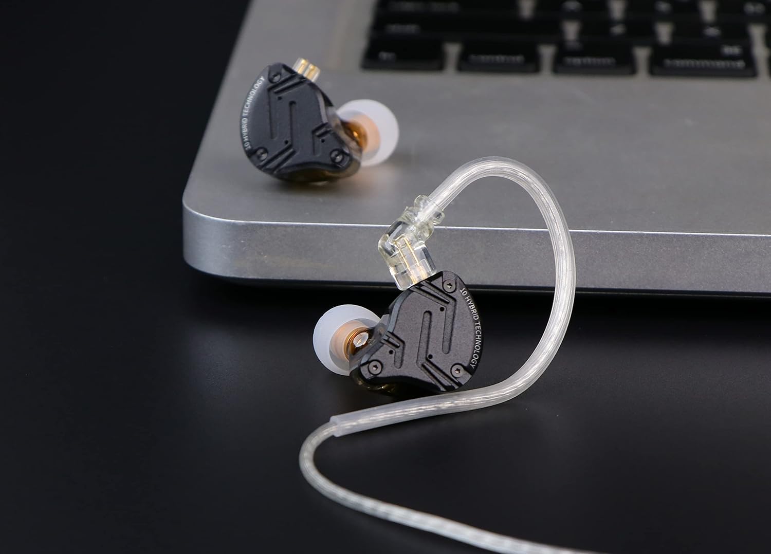 Fones intra-auriculares Linsoul KZ ZS10 PRO X pretos com cabo destacável transparente apoiados próximo a laptop prata.