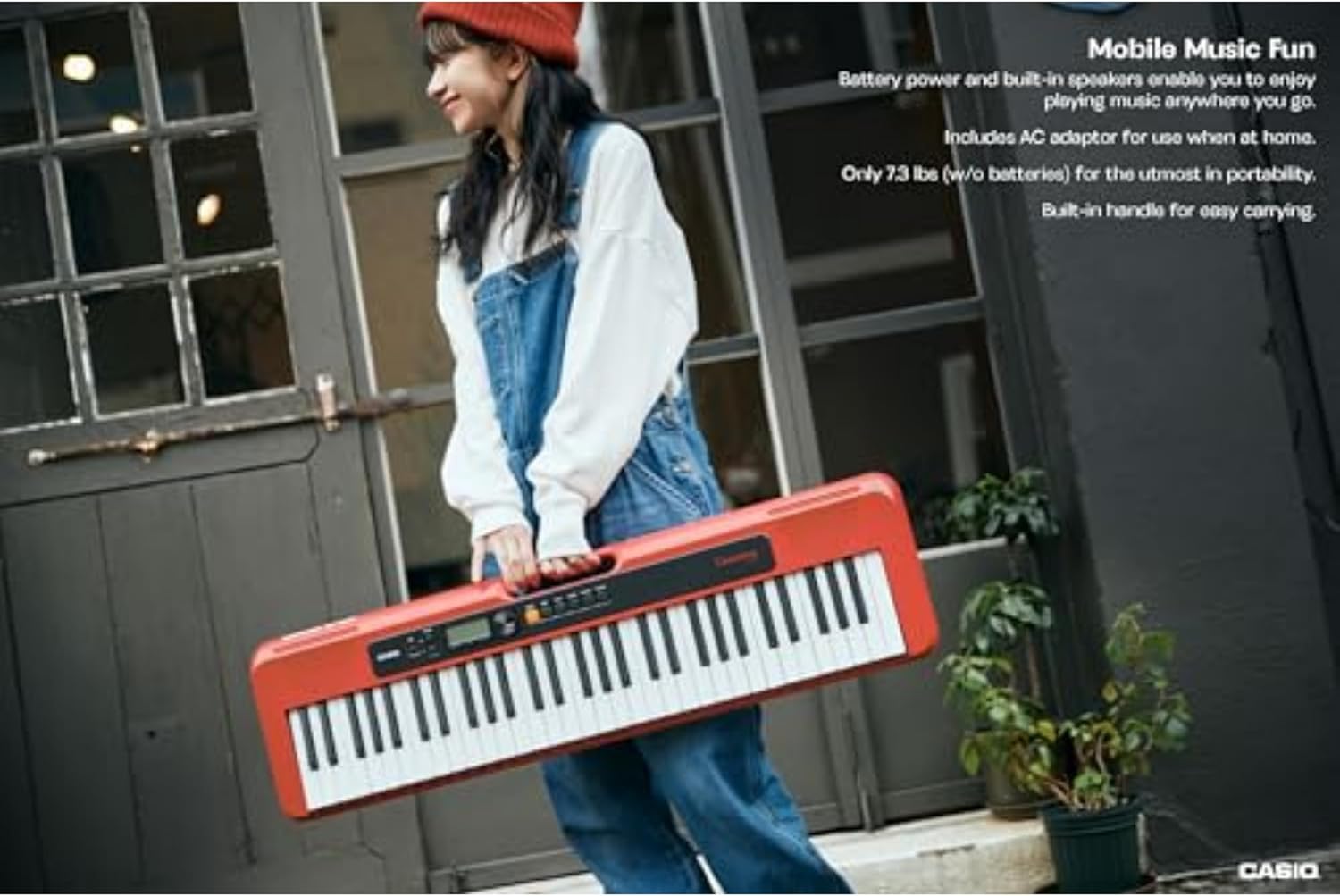 Pessoa carregando teclado portátil Casio Casiotone CT-S200RD vermelho com alça embutida e bateria interna
