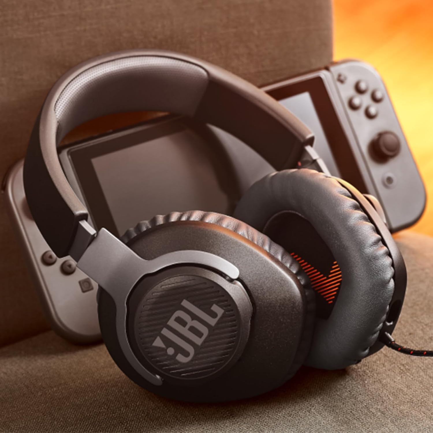 Headset gamer JBL Quantum 100 preto apoiado sobre controle Nintendo Switch