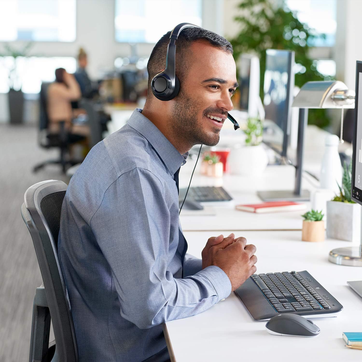Homem usando headset Logitech H390 com fio USB e microfone para comunicação em escritório