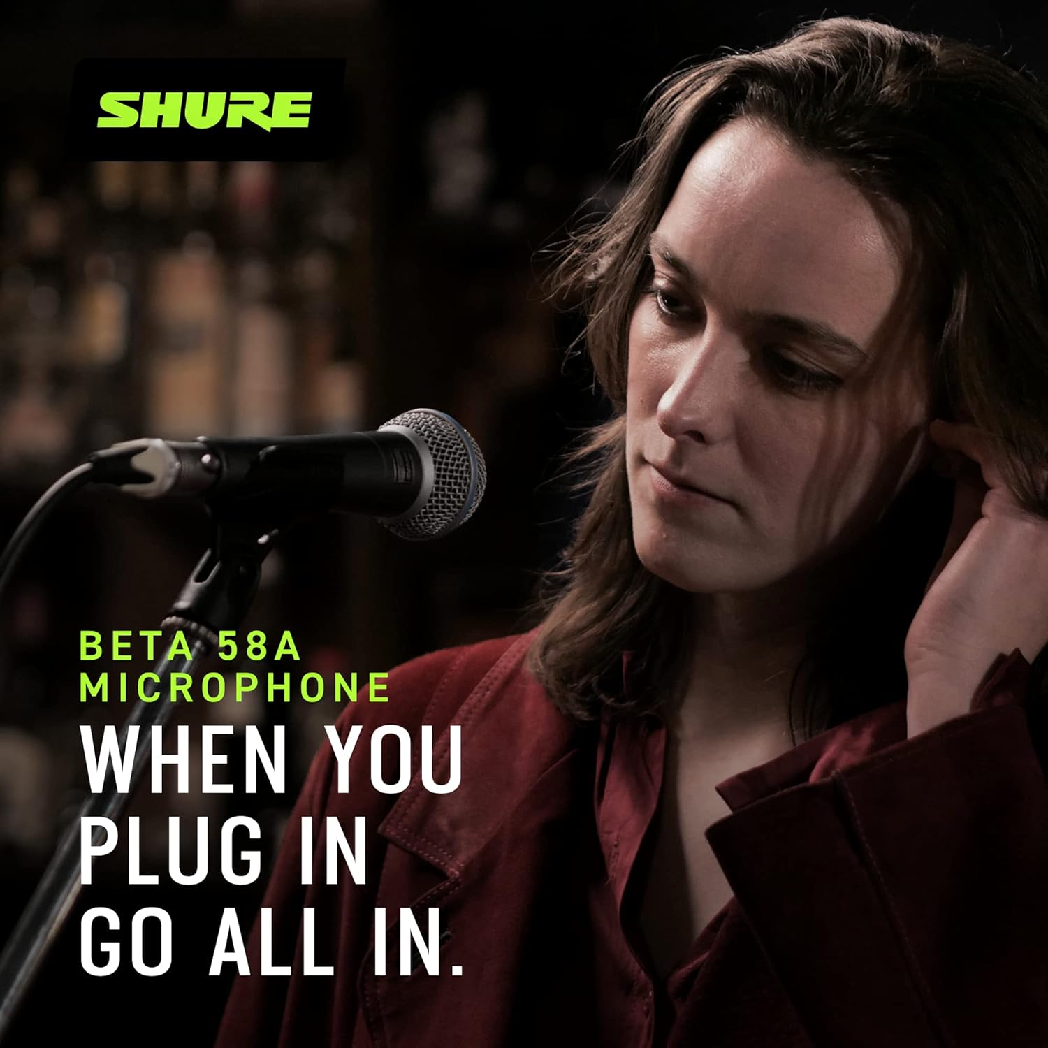 Mulher usando microfone Shure Beta 58A com texto promocional e logo Shure verde em fundo escuro.