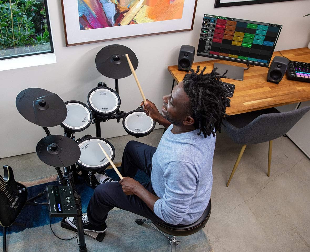 Homem tocando bateria eletrônica Roland TD-07KV com pads brancos e módulo eletrônico.