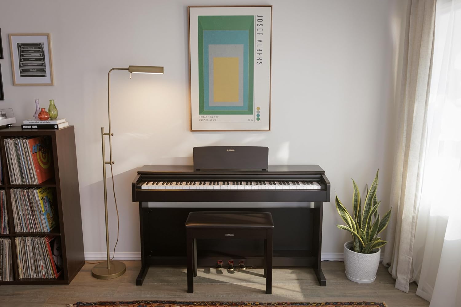 Piano Digital Arius YDP 145 B preto Yamaha em ambiente decorado com planta, estante e iluminação natural