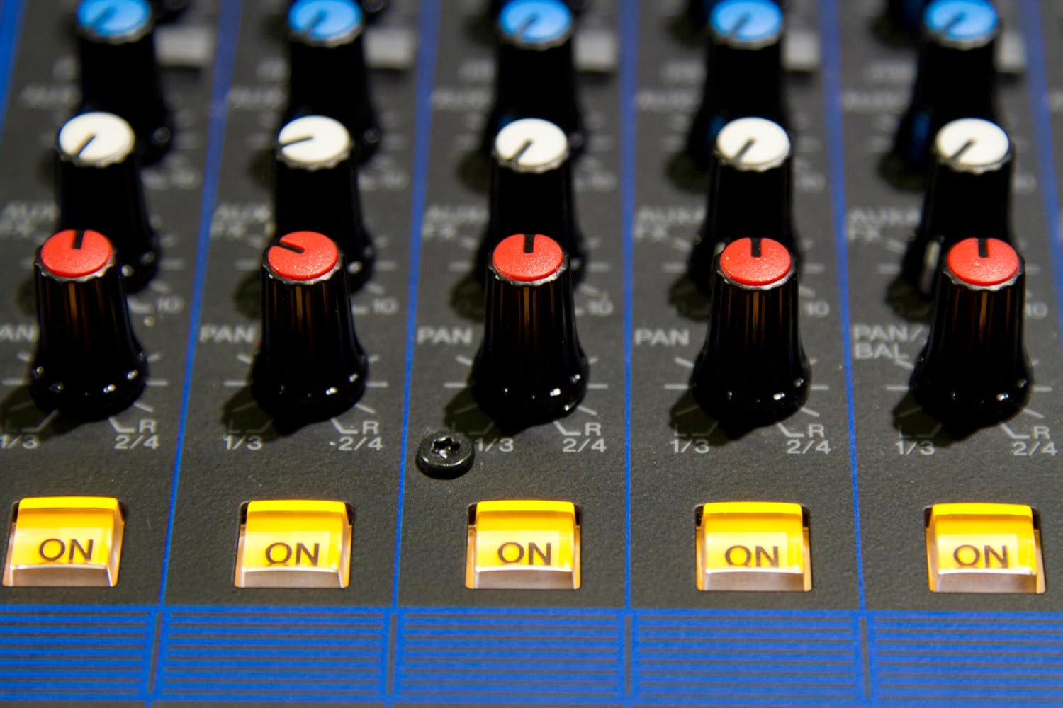 Close-up dos botões de pan, balance e liga/desliga iluminados da mesa de som Yamaha MG12XU