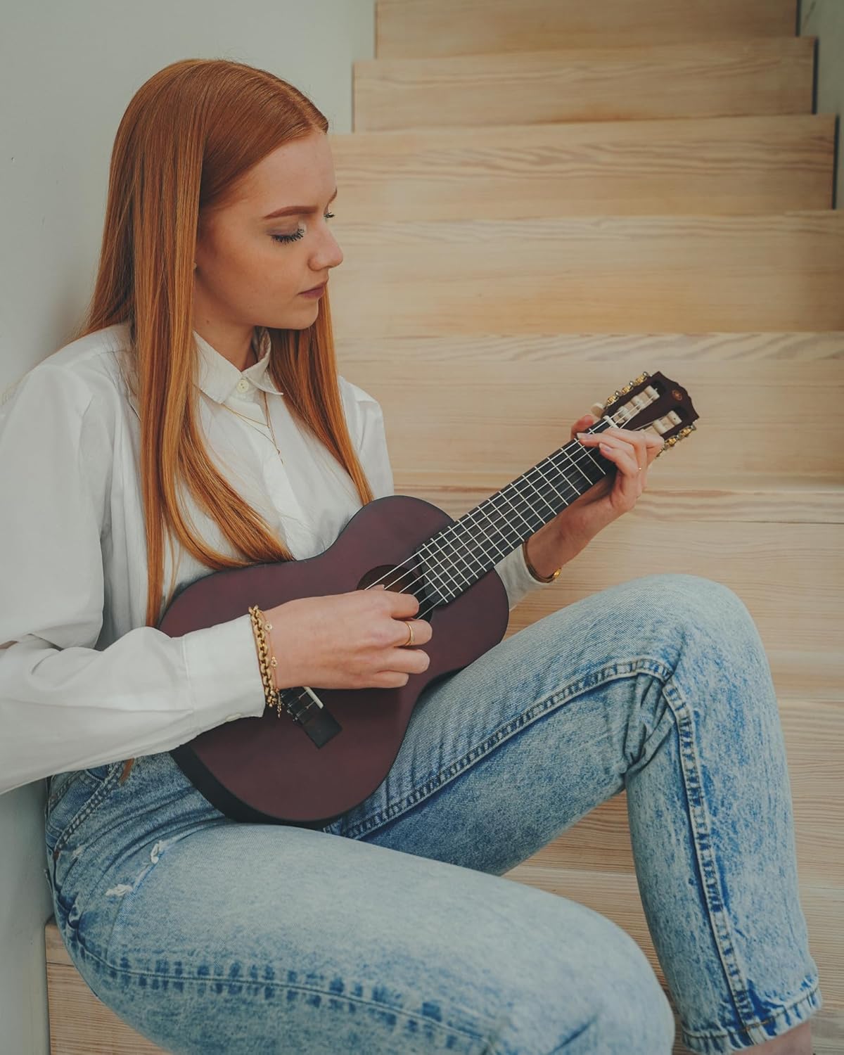 Mulher tocando Yamaha GL-1 Guitalele Tobacco Brown Sunburst sentada em escada