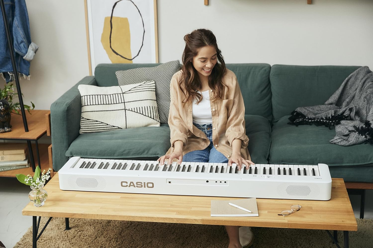 Mulher tocando piano digital Casio Casiotone CDP-S110 branco em sala aconchegante.