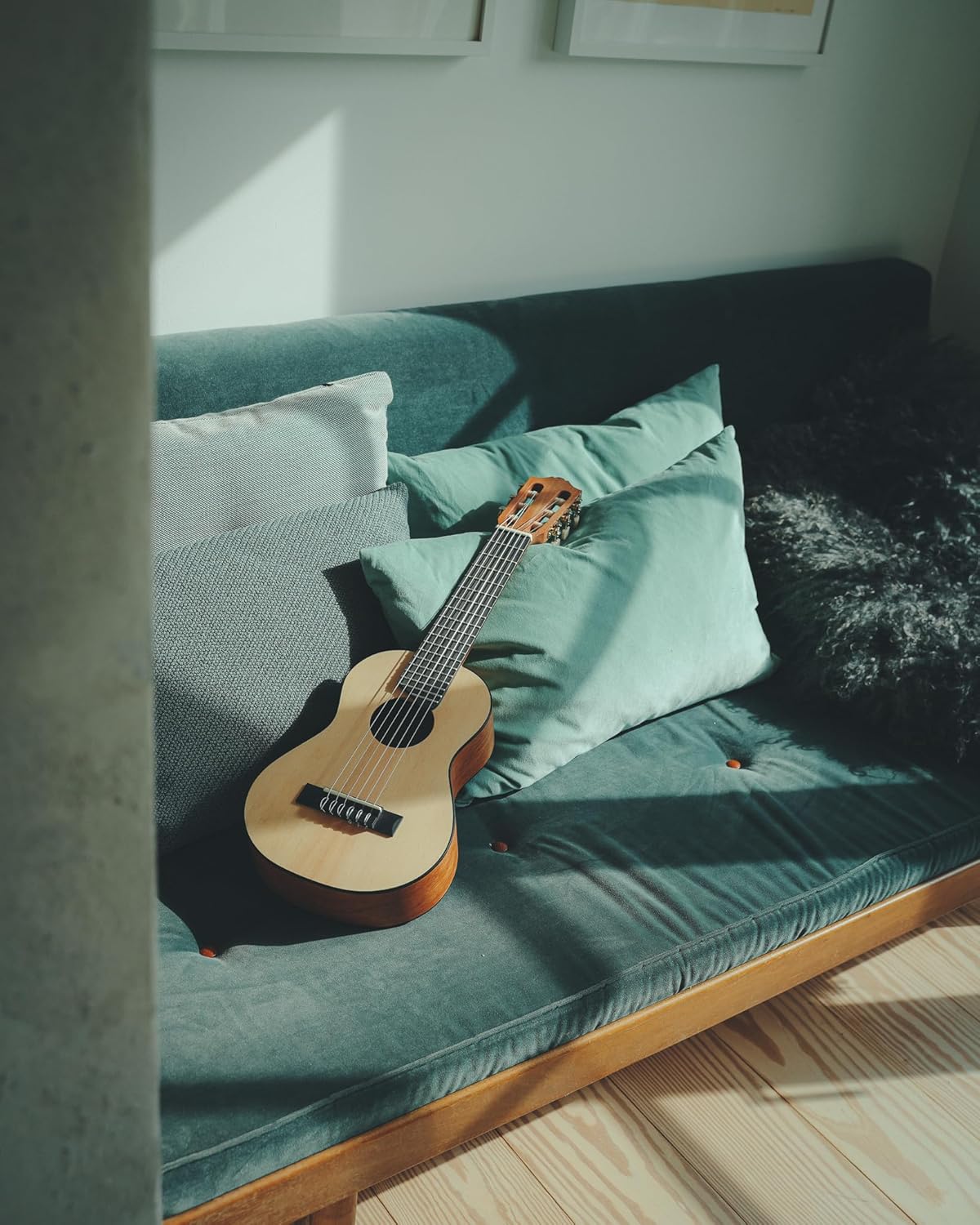 Yamaha GL-1 Guitalele com cordas de nylon sobre sofá verde em ambiente iluminado natural.
