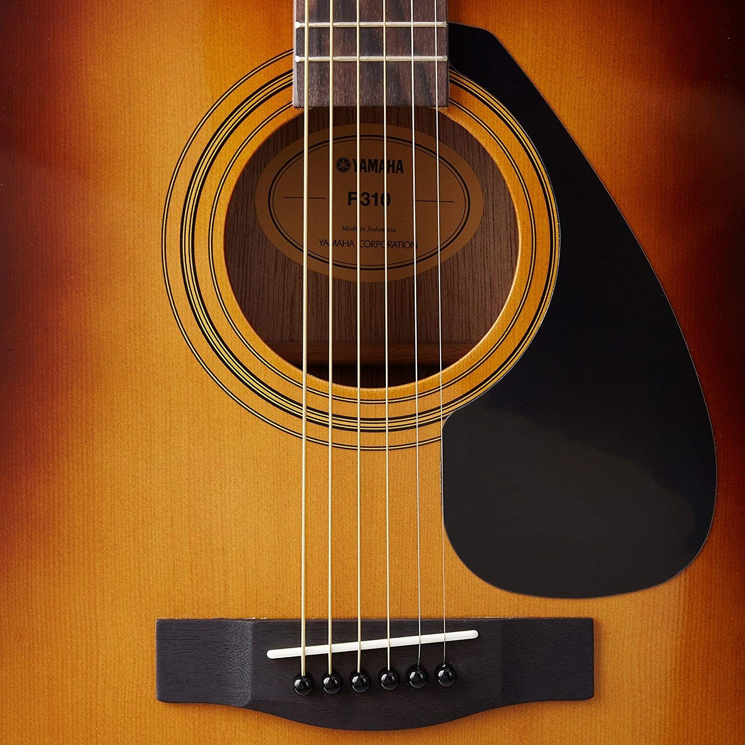 Detalhe do corpo da guitarra acústica Yamaha F310 com label e ponte em madeira escura acabamento Sunburst