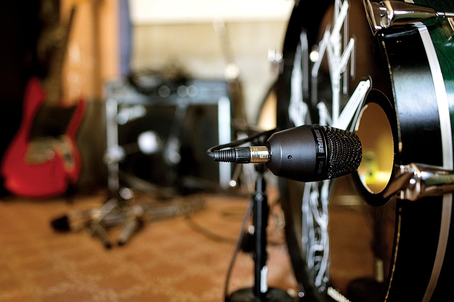 Microfone Shure PGA52 instalado em bumbo para captação de som, com conexão XLR, em estúdio musical.