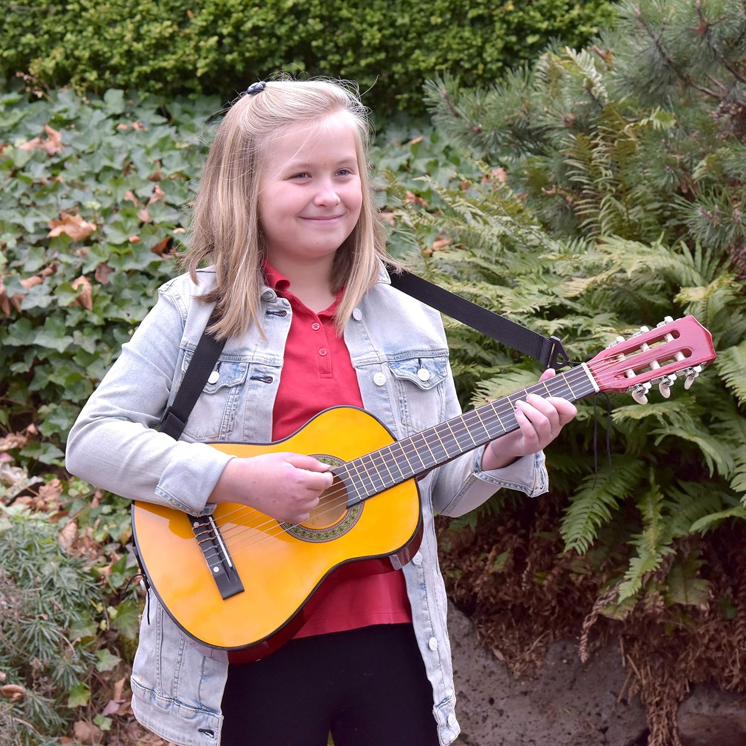 Criança sorrindo e tocando guitarra infantil Master Play ao ar livre com vegetação