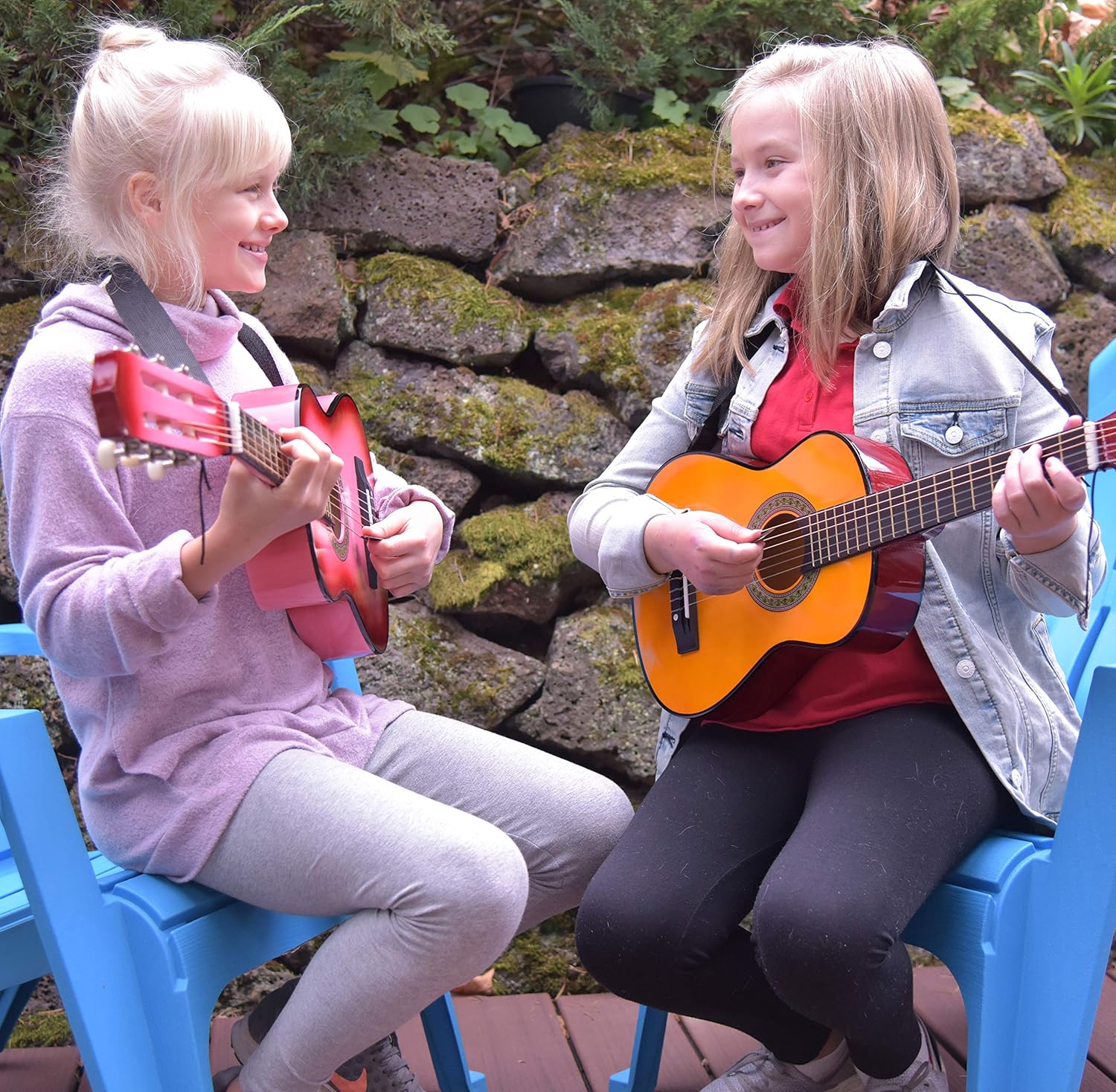 Duas crianças tocando guitarras infantis Master Play sentadas em cadeiras azuis ao ar livre