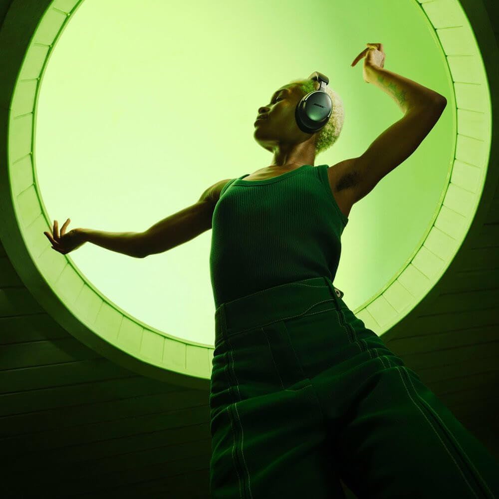 Pessoa usando fones Bose QuietComfort Ultra Wireless preto over-ear em ambiente iluminado verde