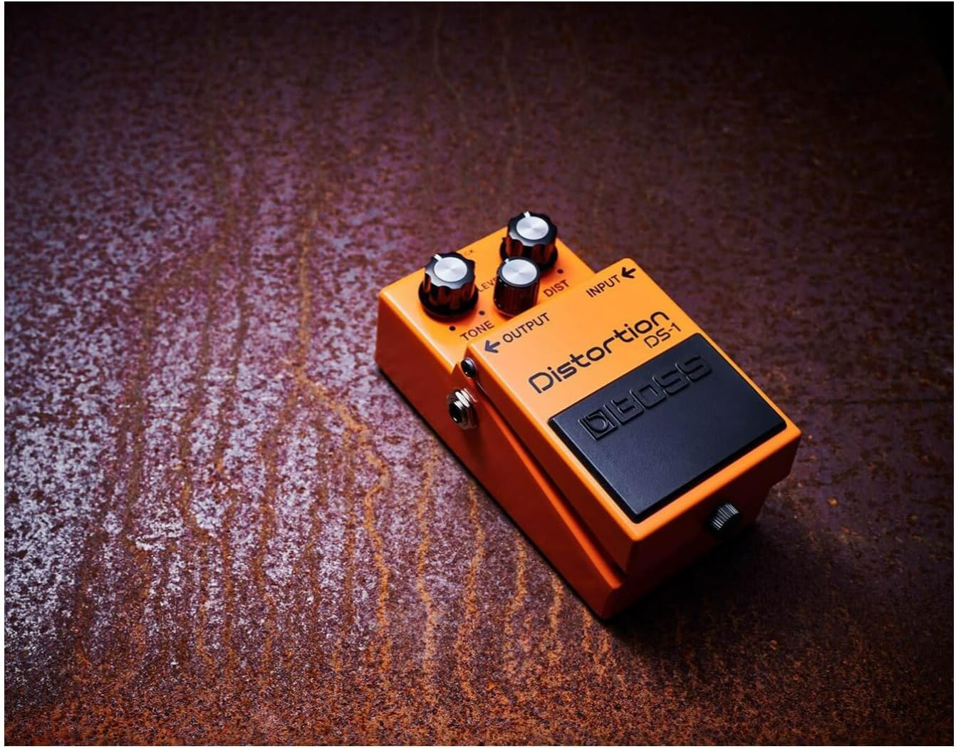 Pedal Boss DS-1 Distortion sobre superfície texturizada com iluminação quente
