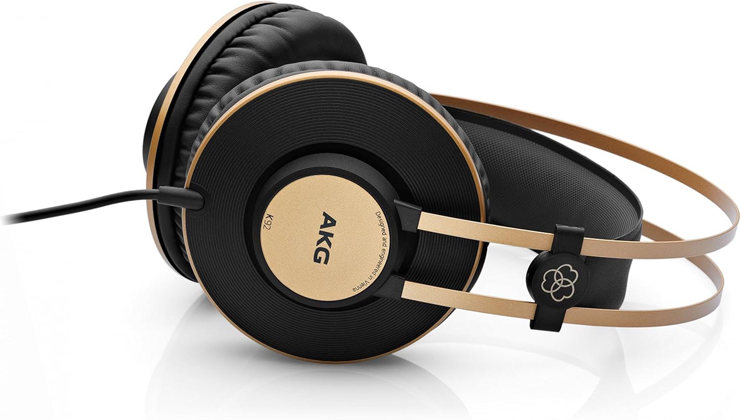 Fone AKG K92 preto com detalhes dourados sobre superfície branca refletiva.